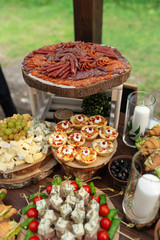 Tasty meals on a brown rustic wooden banquet table. Summer wedding in the forest - 282257776