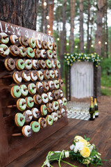 Delicious donuts on wooden stander. Wedding in the forest. Wedding decor. Donuts for guests - 282257929