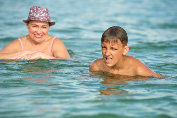 Grandmother and grandson swim together in the sea.