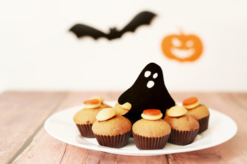 Halloween treats cupcakes on the table against the background of pumpkins and bats