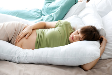 Obraz na płótnie Canvas Young pregnant woman sleeping on maternity pillow at home