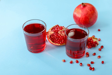 Glasses of fresh pomegranate juice on color background