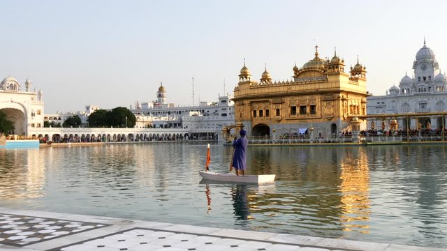 a guard paddles a boat around the pool at golden temple in amritsar, india