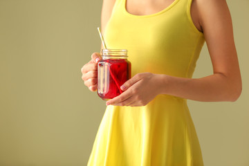 Woman holding mason jar of fresh pomegranate juice on color background