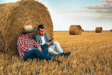 Naklejka na ściany i meble senior farmer with his young colleague on wheat field using tablet