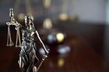 Justice concept. Themis statue, judge's gavel and scale of justice on the gray background.