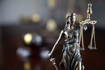 Justice concept. Themis statue, judge's gavel and scale of justice on the gray background.