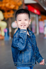 Portrait of little boy dressed jeans jacket smiles at the camera at park in the summer with smiling face. Fashion kid denim , Asia kid