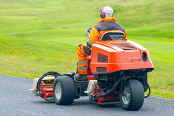 man rides on a special machine to clean the grass of the Golf course