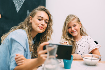 having a great time together. mother and daughter using tablet while having breakfast at home