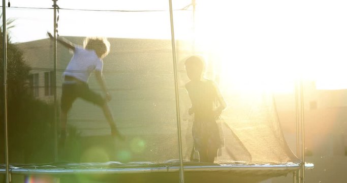 Children jumping inside trampoline outdoors