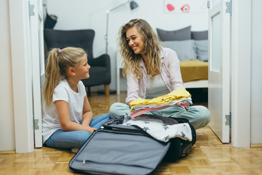 mother and daughter packing suitcase for vacation
