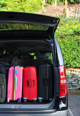 Closeup of back, rear side of black van car carrying  luggage, suitcases. Vertical view.