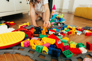 Little girl playing with colorful toy blocks. Educational and creative toys and games for young...