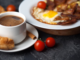 Omelet with slices of bacon and tomatoes in a white plate, a Cup of espresso with croissants. English breakfast