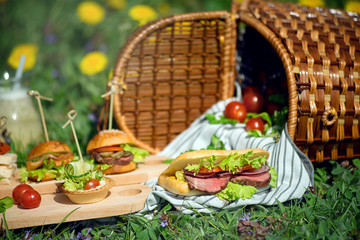 Sandwiches and a snack near to a picnic basket on a sunny day.