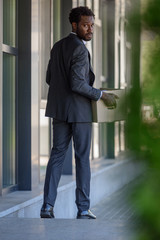 selective focus of dismissed african american businessman looking back while holding cardboard box