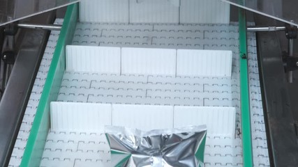 Packs sweets on a production line. Modern Thermo-packaging. Parcel trailer unloading to conveyor belt system