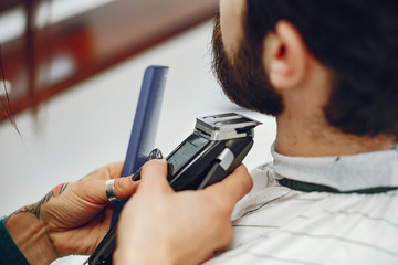 Man with a beard. Hairdresser with a client. Woman with a comb and shaving machine