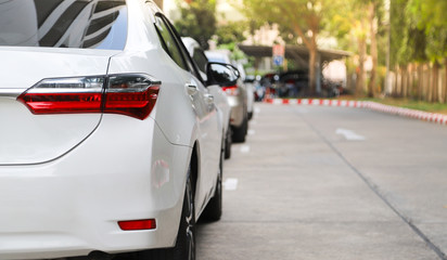 Closeup of rear or back side of white car with  other cars parking in parking area beside the...