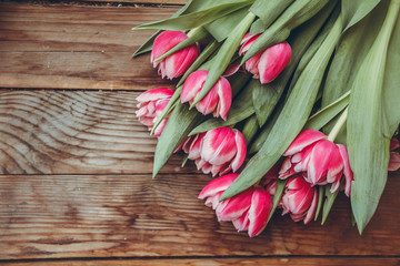 Tulips lie on a wooden table. Close-up. Pink tulips. Raspberry flowers.