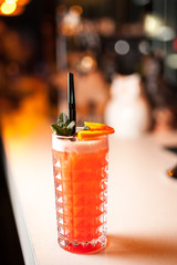 Close-up orange cocktails with orange and mint on the bar, blurred background.