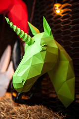 Green paper unicorn on dark background. Origami toy. Origami pegasus. Head of unicorn of paper.