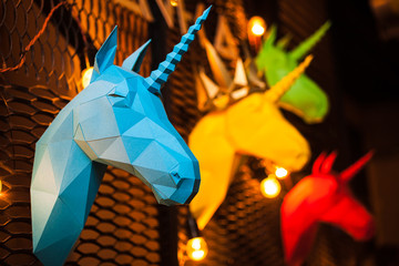 Blue and colorful paper unicorn on dark background. Origami toy. Origami pegasus. Head of unicorn...