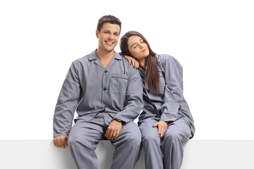Young man and woman in pajamas sitting on a panel