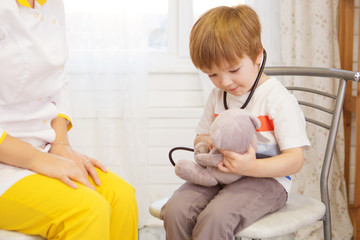 Pediatrician examining baby boy. Doctor using stethoscope to listen to kid and checking heart beat