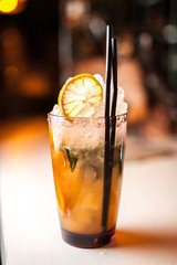 Orange cocktail with orange on the bar, blurred background.