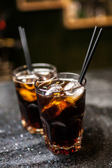 Cocktails in bar, whiskey and cola on dark bar