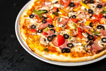 Close-up of a pizza with olives mushrooms with meat and tomatoes