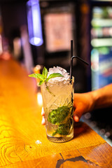 Cocktail with mint and lime on the bar, blurred background.