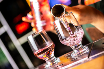 Close-up of expert bartender making cocktail in bar, splash of gin