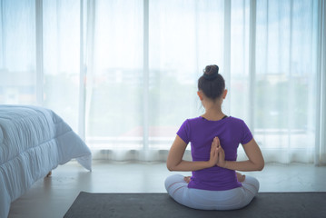 Fototapeta na wymiar A beautiful young woman sitting in a yoga room in a calm and relaxed manner. Light, comfortable, light window background comes in the morning. Health care concepts