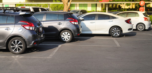 Closeup of rear, back side of brown car with  other cars parking in outdoor parking lot in bright sunny day. 
