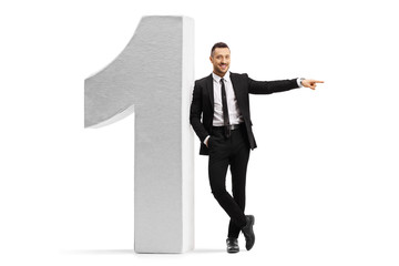 Young businessman leaning on a large number one and pointing to the side