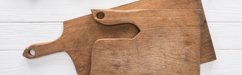 panoramic shot of wooden chopping boards on white table