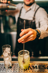 Close-up of expert bartender making cocktail on the bar, blurred background.