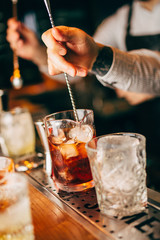 Close-up of expert bartender making cocktail on the bar, blurred background.