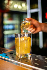 Close-up of expert bartender making cocktail on the bar, blurred background.