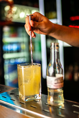 Close-up of expert bartender making cocktail on the bar, blurred background.