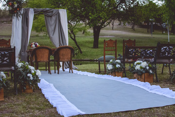 Outdoor wedding ceremony, gray carpet, wooden chairs, flowers and plants. Wedding decoration.