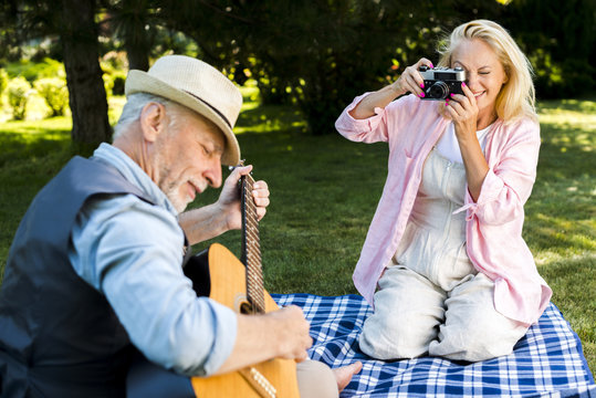 Smiley woman taking a photo to a man with a guitar
