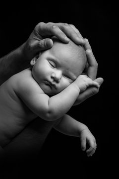 Black And White Portrait Of A Newborn Baby In The Arms Of A Dad