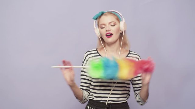 Pinup woman hold duster and dancing. Housekeeper in uniform hold duster. Cleaning retro style purity. Cleaning services.