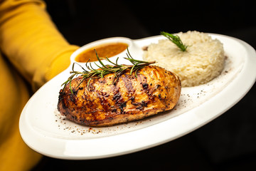 Grilled chicken breast with rosemary and rice on white plate. Proper nutrition. Balanced diet