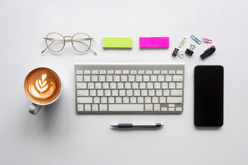 top view office table desk. coffee cup, smartphone, pen, keyboard and other office equipment on white background