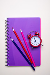 Time management concept. Red vintage alarm clock, pencils and purple  notepad